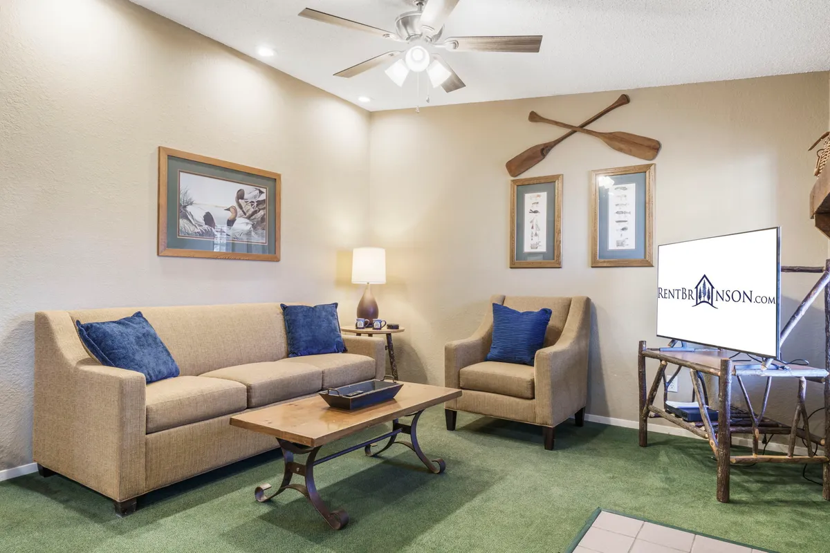 A living area featuring a sofa with blue cushions, a wooden coffee table, art on the wall, a lamp, and a TV on a stand. The space feels comfortable, social, and ideal for both relaxation and accommodating extra guests with the sleeper sofa.