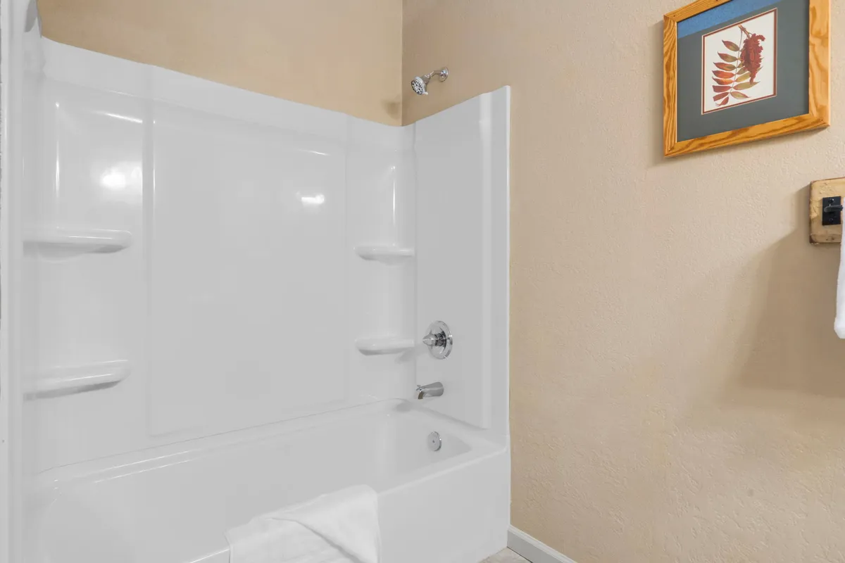 An elegant bathroom scene featuring a bathtub, soft towel, and framed artwork. The ambiance is calm and inviting, perfect for self-care routines and relaxation after a day of adventure.