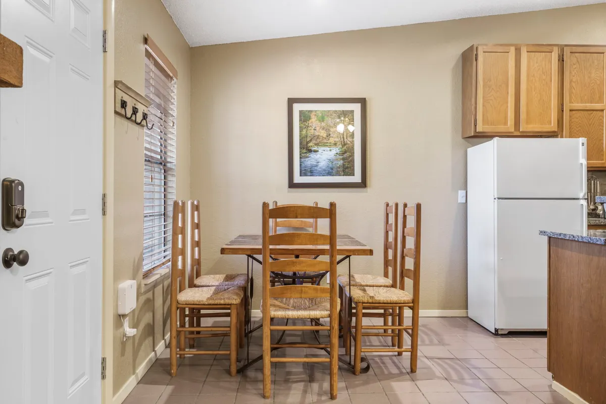 A cozy dining area is featured, centered around a sturdy dining table with comfortable seating and decorative artwork on the wall. The setting suggests a place for family gatherings, shared stories, and laughter-filled meals.