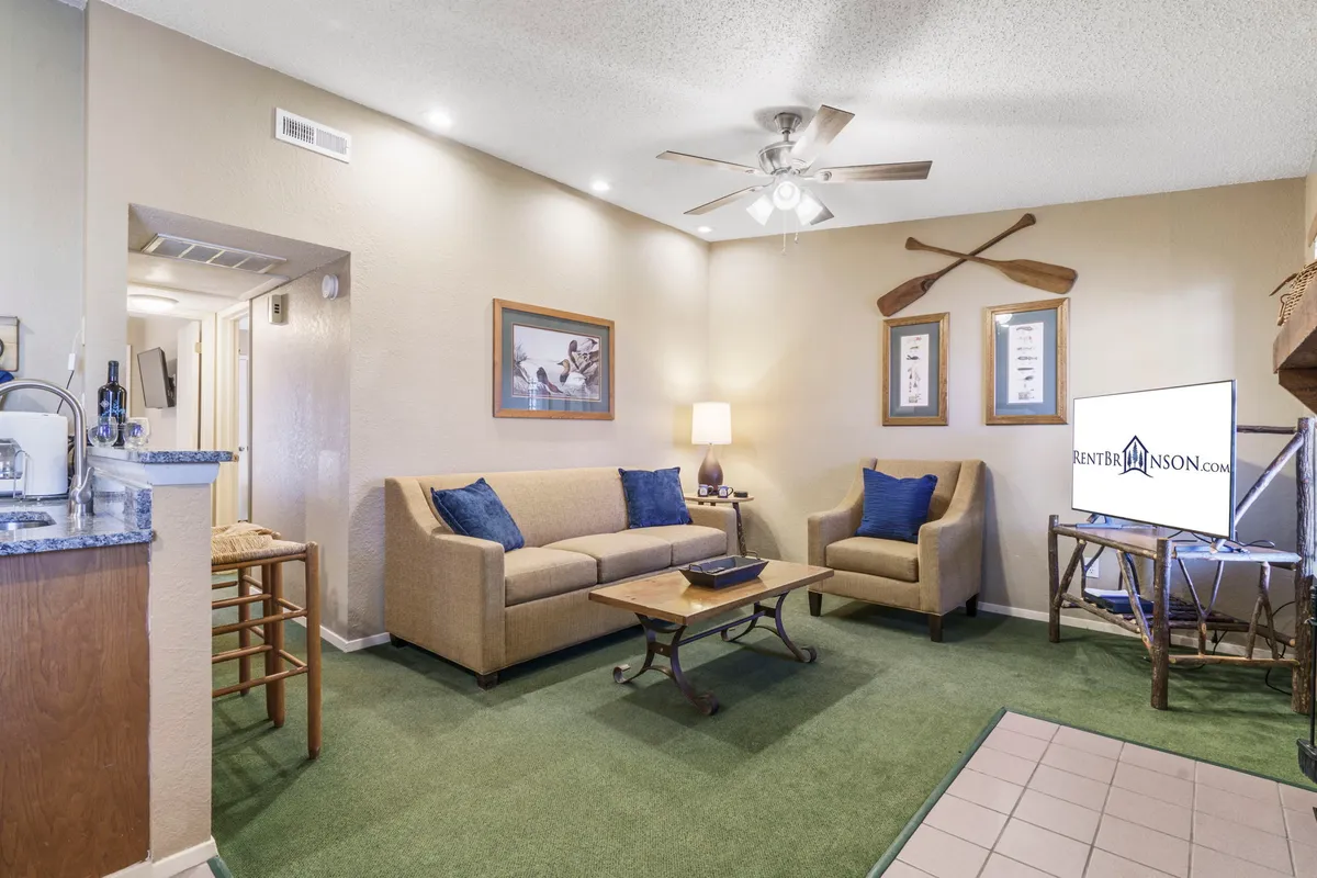 A comfortable living area featuring a soft sofa, coffee table, and nautical decor, including decorative paddles and a lamp. The room exudes a relaxed, welcoming vibe suitable for both quiet moments and group activities like game nights.