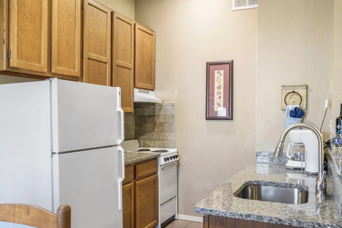 This image showcases a warm and functional kitchen with visible cabinets, a stove, refrigerator, sink, and ample countertop space. The layout supports active meal preparation and makes the kitchen feel welcoming for both everyday cooking and special gatherings.