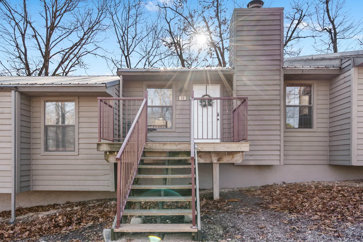 An inviting exterior shot of the property’s front entrance, framed by stairs, a chimney, and mature trees. The porch and steps evoke a sense of welcome and relaxation, suggesting a comfortable base for both owners and pets to rest after exploring.