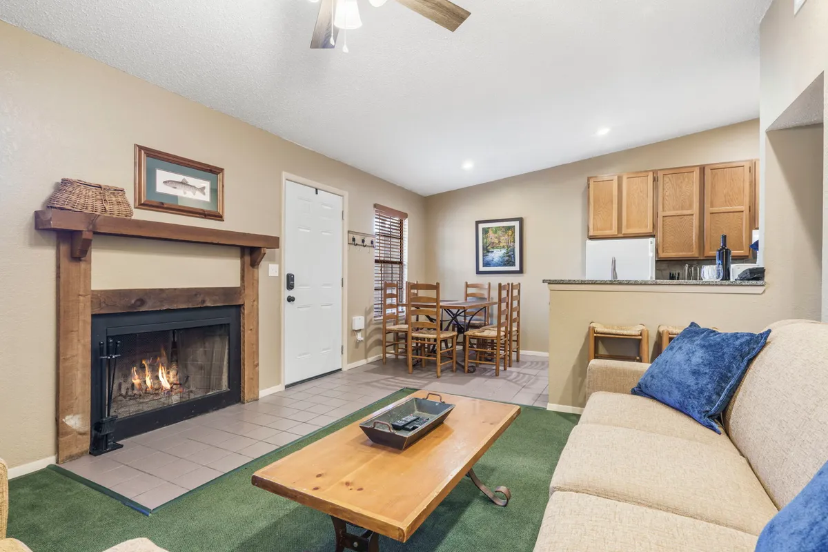 The image showcases a warm, inviting interior with a cozy fireplace, a stylish dining table ready for gatherings, a plush sofa for relaxation, and a modern kitchen counter ideal for meal prep. The scene suggests a space perfect for unwinding, sharing meals, and spending quality time with loved ones.