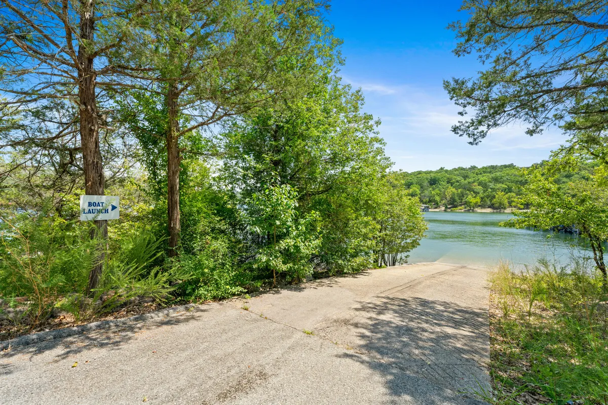 This image features a clearly marked boat launch sign, a boat ramp descending into the water, and tranquil natural surroundings with trees lining the shoreline. The scene evokes the ease and excitement of getting out onto the lake, with the ramp and launch area as focal points.