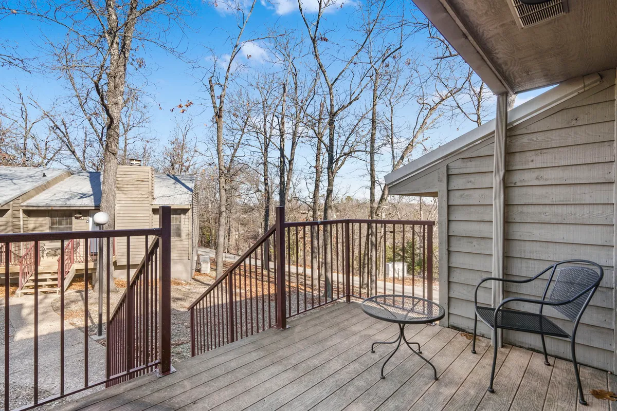 A peaceful private deck with an empty chair and small table, surrounded by trees. The deck offers a serene spot for morning coffee, quiet conversation, or enjoying sunsets while looking out at the surrounding woods.